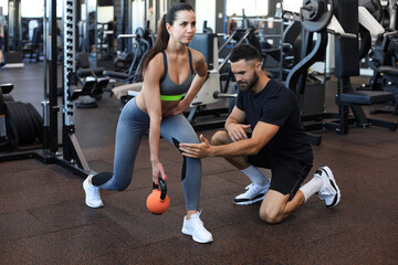 Fitness instructor exercising with his client at the gym.