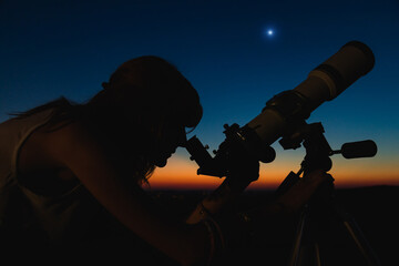Wall Mural - silhouette of a woman and telescope with twilight sky.