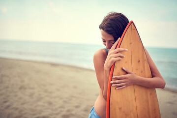 Wall Mural - A young female surfer posing with her board