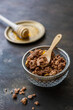 © Sonja Rachbauer - Knuspriges Granola in einer Glasschüssel mit einem Holz Löffel, Honig auf einem goldenen Teller, Nahaufnahme, rustikaler Hintergrund