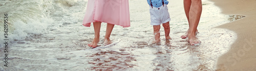 Fotografía Family Father mother and little son walk barefoot along the seashore on the wet sand at the water's edge cropped