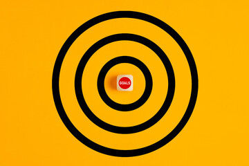 Poster - Target with the word goals written on a wooden block as the bulls eye on yellow background. Concept of achieving or targeting business goals.