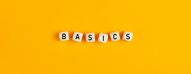Basics word written on wood blocks on yellow background with flat lay view