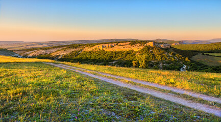 Canvas Print - Hilly terrain with ravines and dirt road