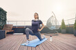 Beautiful young woman practicing yoga on rooftop terrace