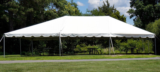 Wall Mural - Empty event tent with trees and blue sky in the background and a grassy foreground.