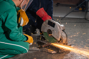 Wall Mural - Professional mechanic man is cutting steel metal with rotating carbon blade cutter. Steel industry and workshop concept.