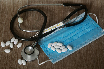 disposable medical mask, white tablets, mercury thermometer, stethoscope. The concept of cost of health