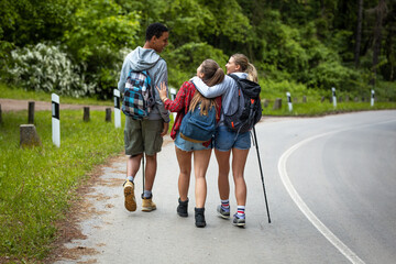 Wall Mural - group of friends hiking in nature.they walking by the old country road.