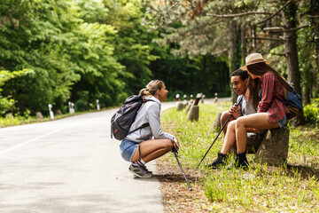 Wall Mural - group of friends hiking in nature.they sitting and resting by the old country road.