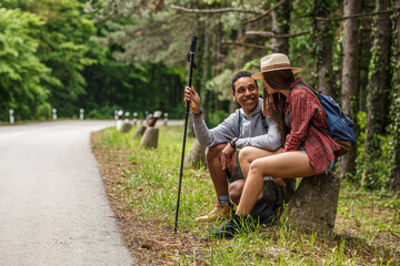 Wall Mural - young couple hiking in nature.they sitting and resting by the old country road.