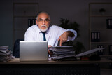 Fototapeta  - Old male employee working late at workplace