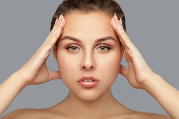 Portrait of a beautiful woman with  brown hair, beautiful fresh make-up and with healthy clean skin on a gray background. Make-up and cosmetology concept.