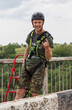 a guy in the helmet and special equipment is very happy before rope jumping from the bridge