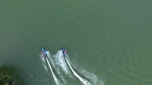 Two people on jetsurf boards racing each other around a watersport recreational area, aerial god view, slow motion