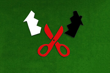 Red scissors that cut the house into two halves white and black on a green background. Real estate section. share ownership.