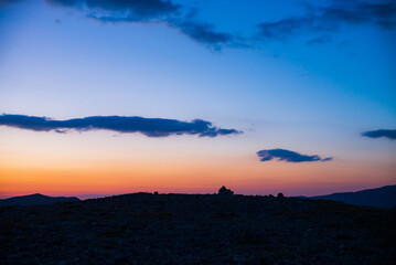 Wall Mural - atmospheric dawn landscape with dark silhouette of tour on pass top under vivid orange pink lilac gr