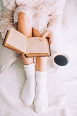 Canvas Print - Young woman on the bed with old book and cup of coffee enjoys her stay.