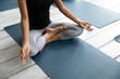 Close up top above view young african american woman in sportswear sitting barefoot on floor mat in padmasana lotus pose with folded fingers mudra sign on knees, enjoying meditating at yoga class.