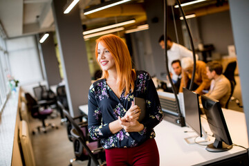 Wall Mural - Young businesswoman holding a digital tablet while in the background team working in the modern office