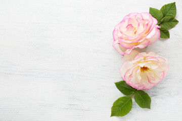 Sticker - Two  Roses with leaves on a  shabby wooden table. Flat lay.