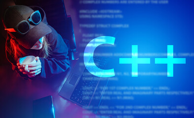 C++ programming language. Large C++ lettering and a girl in a baseball cap at a laptop. Development of computer applications. The job of the programmer. C plus plus.