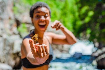 BIPOC woman holding an orange butterfly