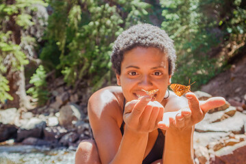 BIPOC woman holding an orange butterfly