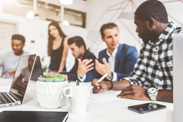 Wall Mural - A team of young office workers, businessmen with laptop working at the table, communicating together in an office. Corporate businessteam and manager in a meeting. coworking.