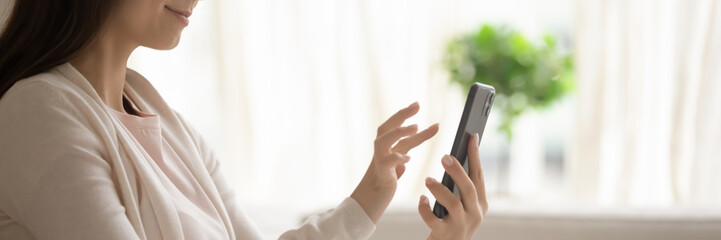 Satisfied young woman holding smartphone, browsing mobile device app close up cropped wide image, beautiful girl using phone, writing message in social network, shopping online, playing game