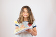 Pretty little girl in striped shirt writing in a notebook