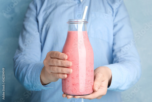 Fotografía Woman holding tasty strawberry smoothie on light blue background, closeup