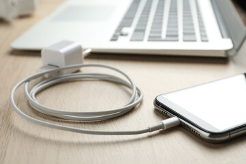 smartphone and usb charger on wooden table, closeup. modern technology