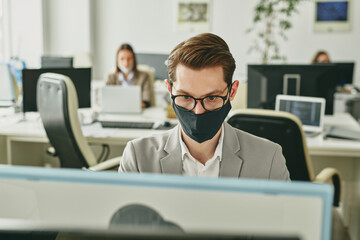 Poster - Contemporary young businessman in eyeglasses and protective black textile mask