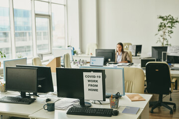 Poster - Paper with announcement about work from home on one of computer monitors
