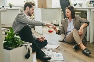 Poster - Young businessman pouring whiskey into woneglass held by his female colleague