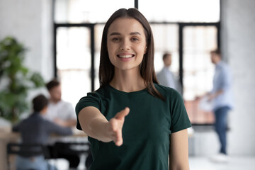 Wall Mural - Head shot portrait pretty friendly employer stretch out her hand for hand shake greets applicant, representative of company young confident executive manager welcoming client express respect concept