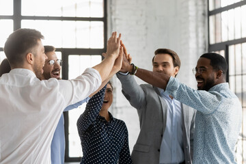 Multi racial millennial affiliates join hands giving high five celebrating common business success sales growth department promotion feels excited and motivated showing team spirit and synergy concept