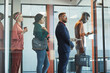 canvas print picture - Side view at multi-ethnic group of business people standing in line in office behind glass wall, copy space