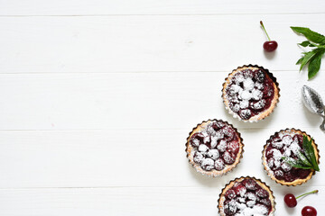 Wall Mural - Tartlets with berries on a white wooden background. View from above.