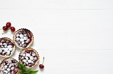 Wall Mural - Tartlets with berries on a white wooden background. View from above.