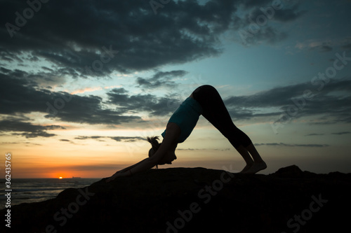 Fotografía Woman doing yoga exercises on the ocean coast at amazing twilight