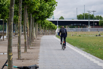 Wall Mural - Male cyclist ride bicycle on bicycle lane on promenade riverside of Rhein River in Düsseldorf, Germany. Cycling friendly city in europe. Eco friendly mobility transportation.