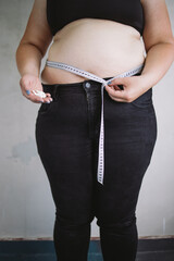 Wall Mural - Weight loss, diet, healthy lifestyle. Overweight woman measuring her waistline with tape and taking dietary supply