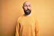 © Krakenimages.com - Handsome bald man with beard wearing casual sweater standing over yellow background smiling looking to the side and staring away thinking.