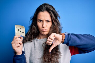 Sticker - Young beautiful woman with curly hair holding reminder paper with lol message with angry face, negative sign showing dislike with thumbs down, rejection concept