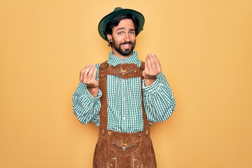 Young handsome man wearing tratidional german octoberfest custome for Germany festival doing money gesture with hands, asking for salary payment, millionaire business