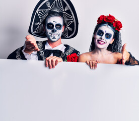 Canvas Print - Young couple wearing mexican day of the dead costume holding blank empty banner smiling friendly offering handshake as greeting and welcoming. successful business.