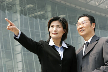 A woman in business suit showing something to a bespectacled man