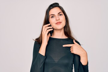 Poster - Young beautiful woman having a conversation talking on smartphone ove isolated background with surprise face pointing finger to himself